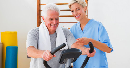 Caregiver is teaching the old man how to exercise